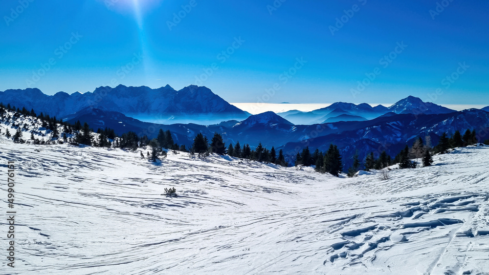 Panoramic view on snow capped mountain peaks of Karawanks in Carinthia, Austria. Julian Alps. Winter wonderland in the Austrian Alps, Europe. Ski tour, snow shoe hiking. Hochobir. Blue misty hills.