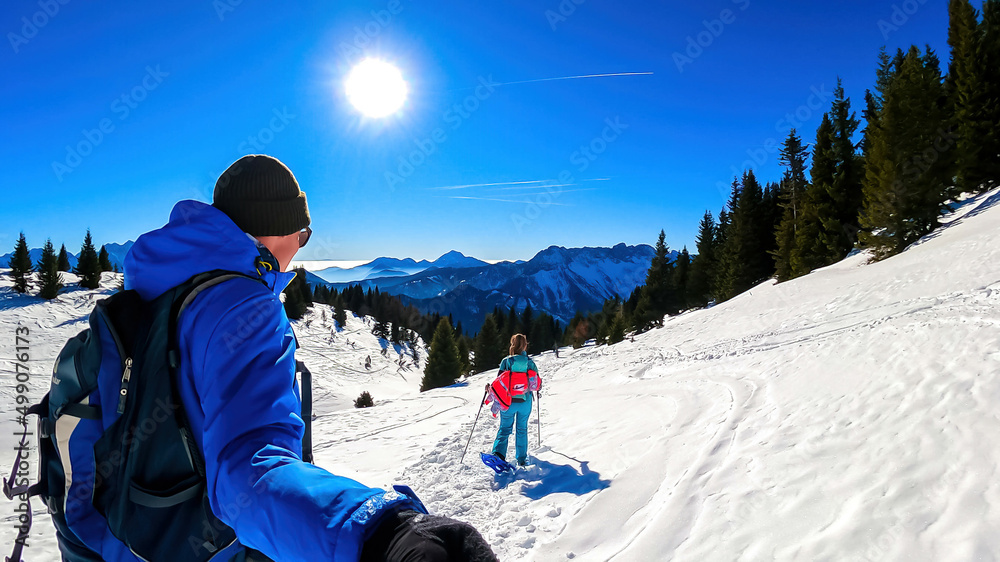 Active couple snow shoe hiking on a trail with scenic view on snow capped mountain peaks of Karawanks in Carinthia, Austria. Ski tour. Sunny winter day. Freedom. Winter wonderland, Hochobir. Selfie