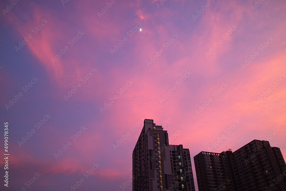 Romantic sunset sky over the city with a bright quarter moon