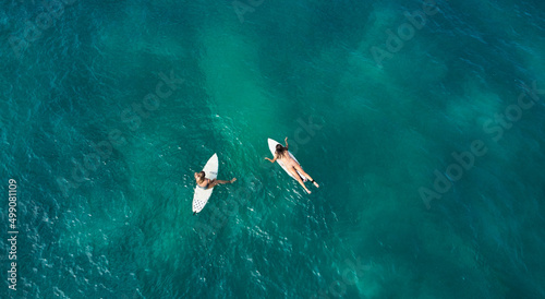 Aerial view of the ocean and surfer girls.