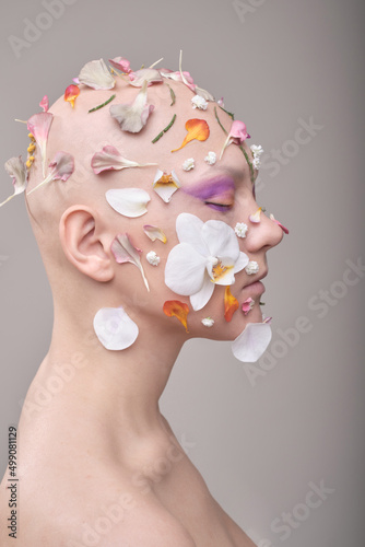A beautiful woman without hair with flowers on her head, a conceptual photo with an unusual model