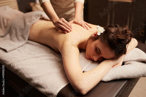The masseuse gives a body massage to a young woman. Spa relaxation concept. photo