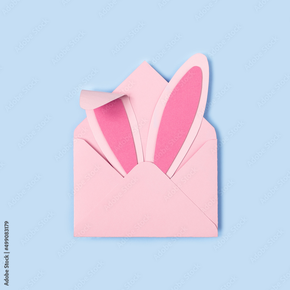 Happy Easter. Bunny rabbit ears made of pink paper in pink envelope on blue background. Easter greeting card with envelope. Happy Easter minimal concept with copy space. Square format, Flat lay Happy Easter. Bunny rabbit ears made of pink paper in pink envelope on blue background. Easter greeting card with envelope. Happy Easter minimal concept with copy space. Square format, Flat lay