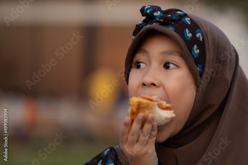 Muslim girl eating pizza in the farm