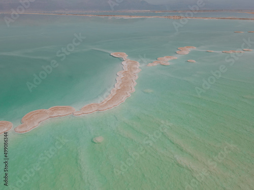 Aerial shoot of Salty islands of Dead Sea among mirror smooth water with Jordan mountains on the horizon. Seascape  Nature background. Israel