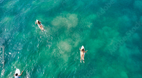 Aerial view of the ocean and surfer girls.
