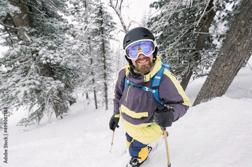 Portrait of Skier in winter forest. Winter beautiful landscape in ski resort, fir trees covered with snow Portrait of Skier in winter forest. Winter beautiful landscape in ski resort, fir trees covered with snow