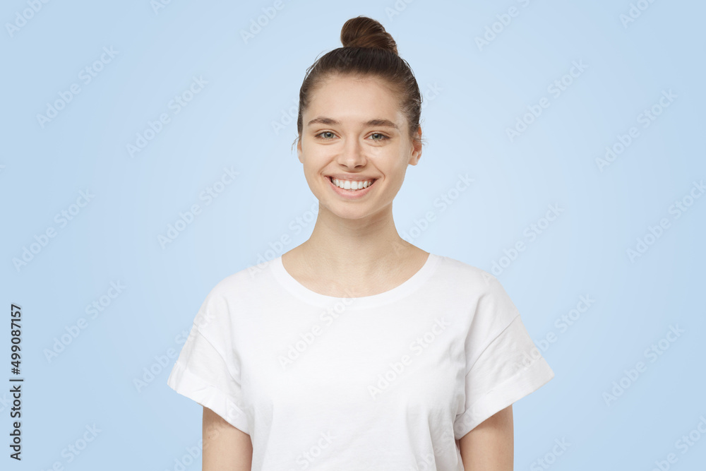 Smiling young woman in white t-shirt looking at camera, isolated on gray background Smiling young woman in white t-shirt looking at camera, isolated on gray background
