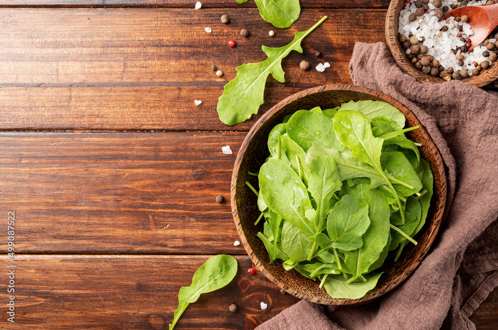 Fototapeta premium Fresh arugula leaves in brown bowl top view