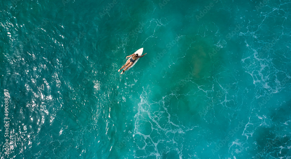 Aerial view of the ocean and surfer girl.