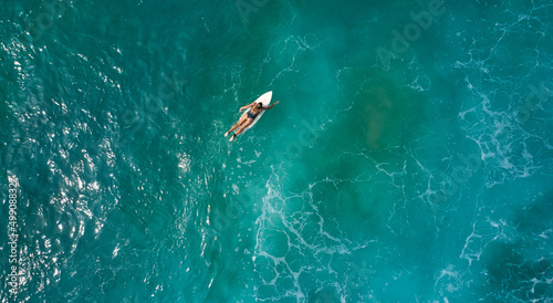 Aerial view of the ocean and surfer girl.