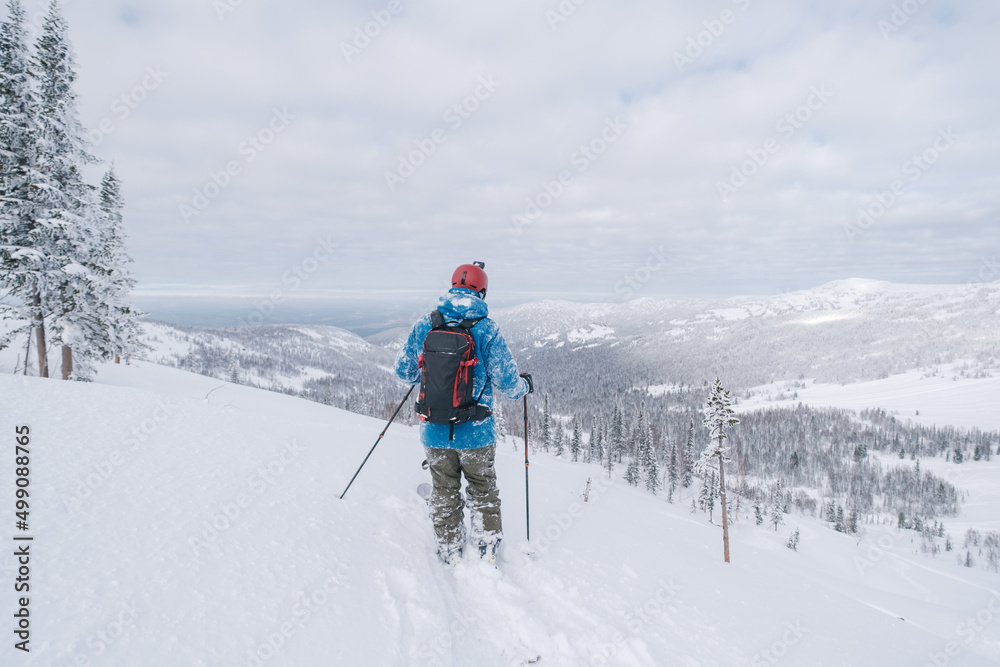 Skier moving in snow powder in forest on a steep slope of  ski resort. Freeride, winter sports outdoor