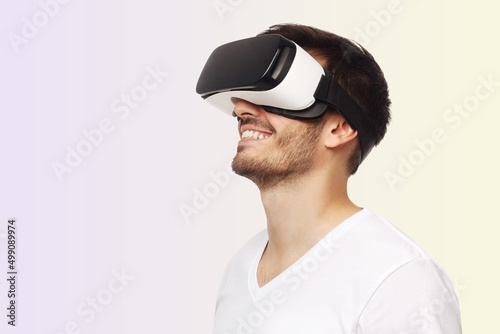 Young happy man smiling while enjoying and experiencing virtual reality with VR headset © Damir Khabirov