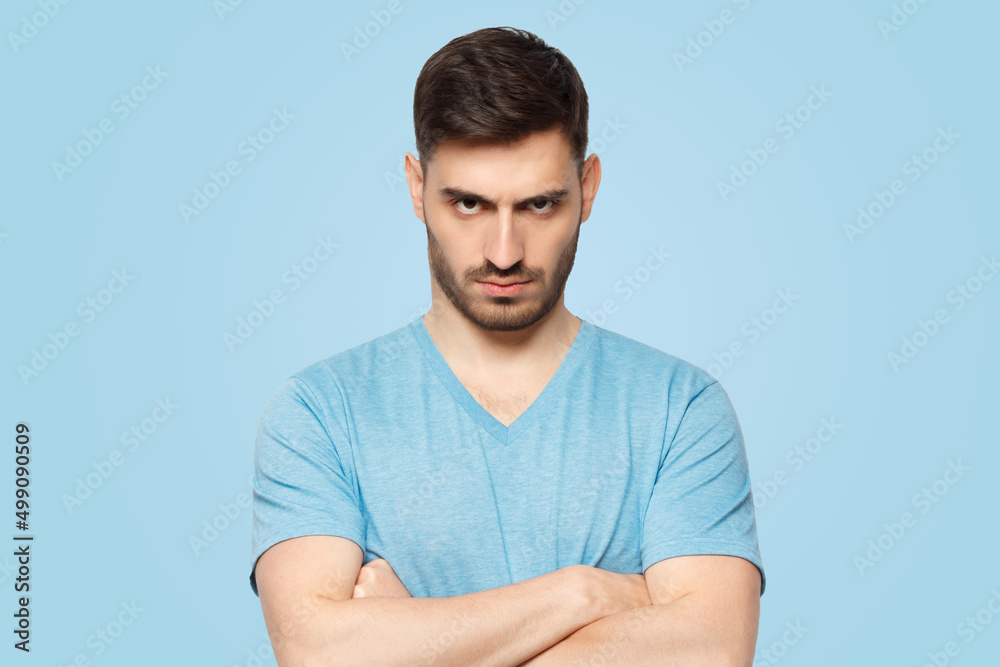 Obraz premium Young aggressive man standing with arms crossed and serious concentrated face