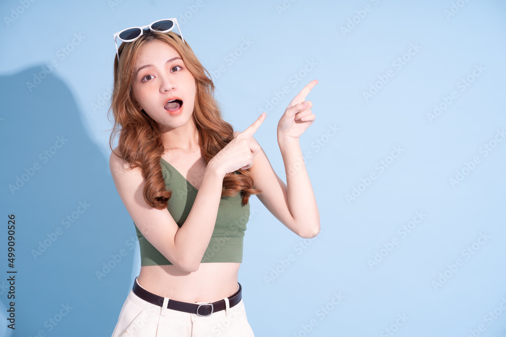 Beautiful young Asian woman on blue background, summer vacation concept Beautiful young Asian woman on blue background, summer vacation concept