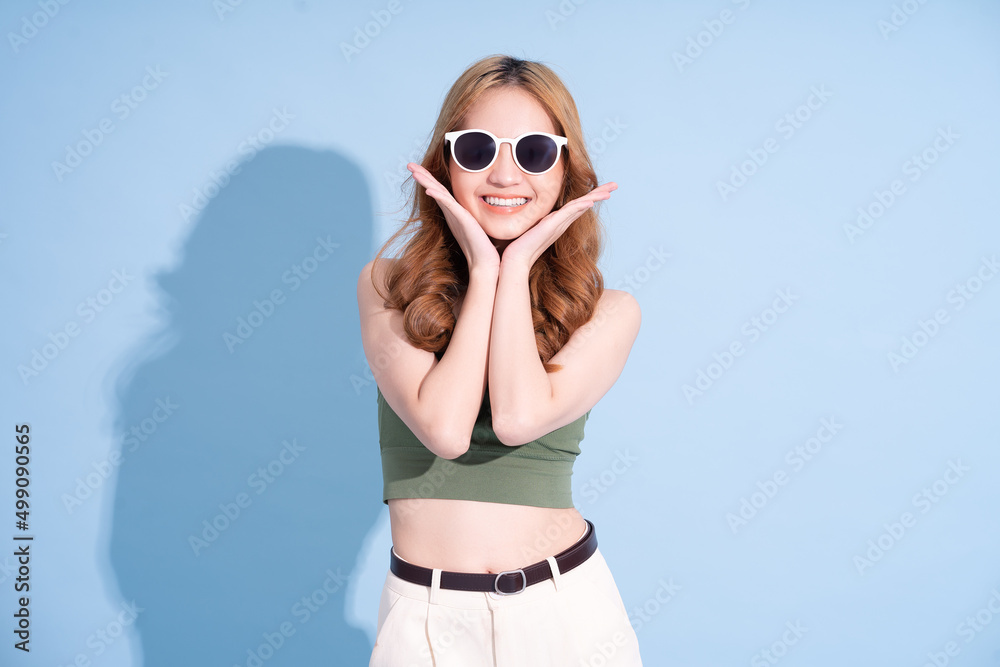 Beautiful young Asian woman on blue background, summer vacation concept