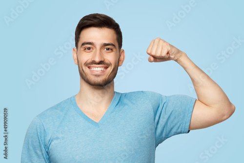 Foto Young strong sporty athletic man in casual blue t-shirt, showing biceps after tr
