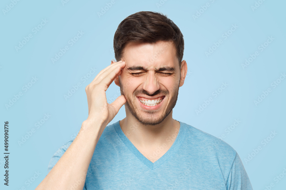 Young man showing how much his head hurts, experiencing pain Young man showing how much his head hurts, experiencing pain