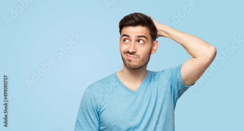 Young doubtful man thinking, scratching head and trying to find solution