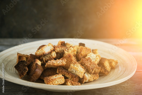 Wooden plate with fried breadcrumbs dark background in rays sun. Rustic setting and food.