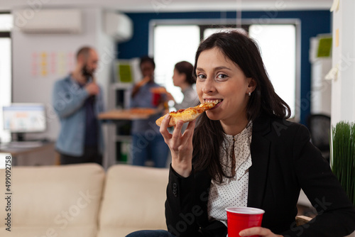 Portrait of business woman celebrating with drinks after work, meeting with colleagues in startup office. Young adult enjoying pizza and beer beverage at fun party celebration.