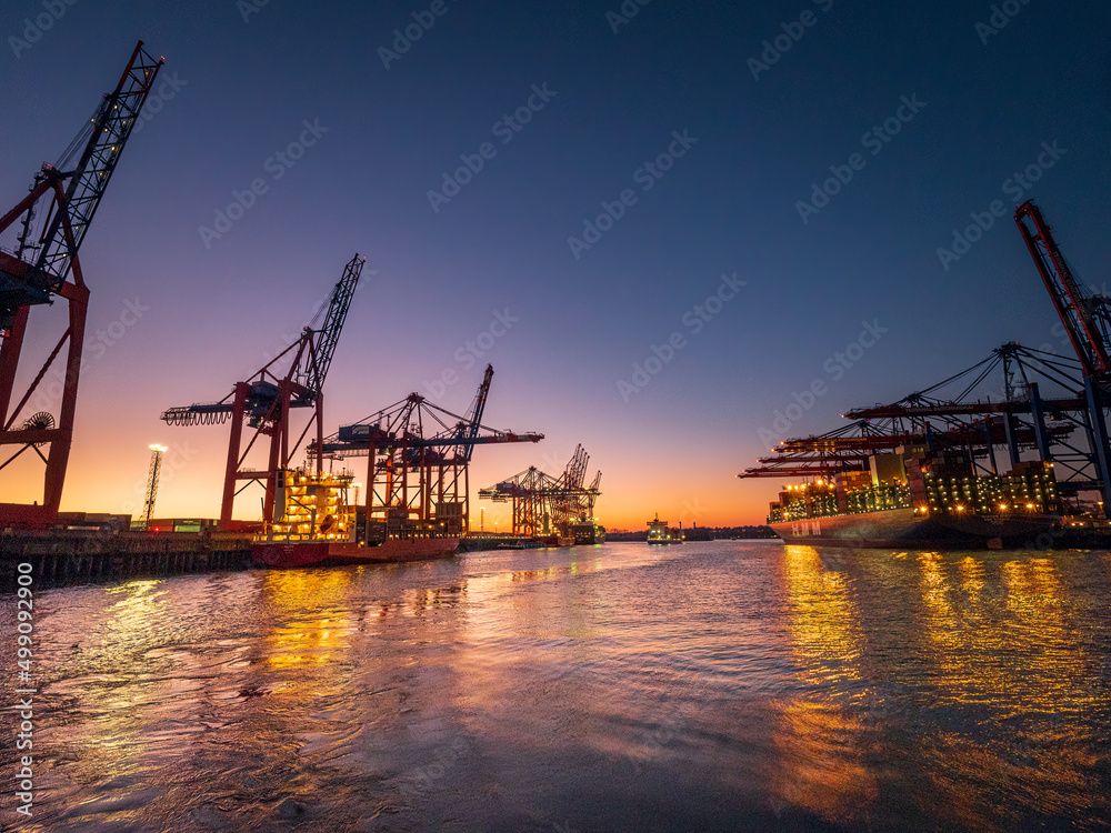 Hamburg industrial city shape during sunset with stunning orange light and silhouette machines