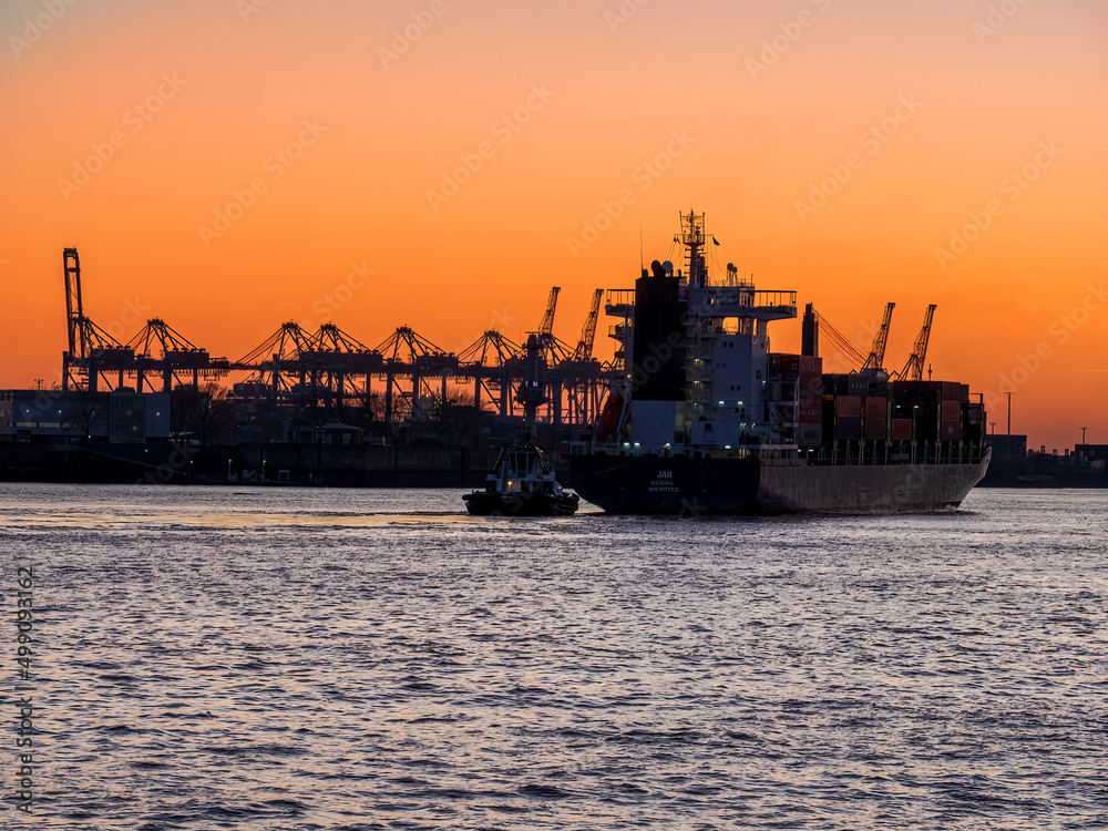 Hamburg industrial city shape during sunset with stunning orange light and silhouette machines