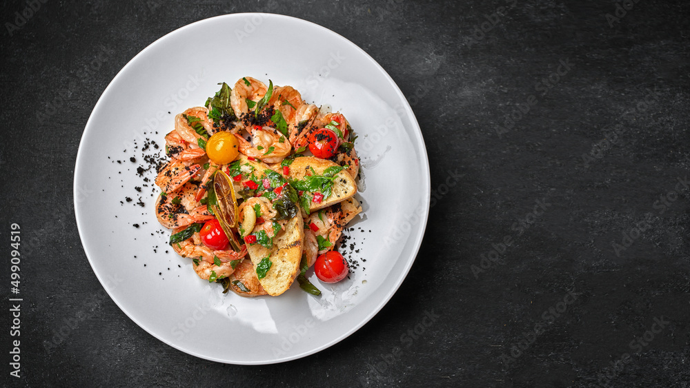 Fried shrimp with toast and tomatoes, on a plate, on a dark background with space for text Fried shrimp with toast and tomatoes, on a plate, on a dark background with space for text