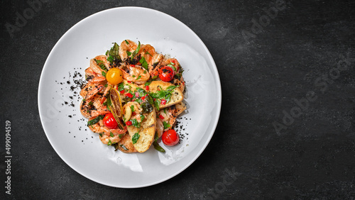 Fried shrimp with toast and tomatoes, on a plate, on a dark background with space for text