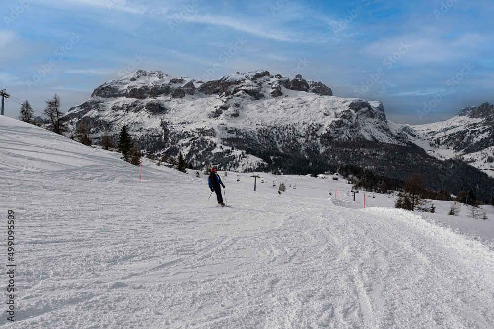 Skier having Fun on a Snowy Ski Slope in the Italian Dolomites Mountains and Chair Lift  in the distance