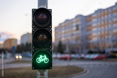 Traffic green light letting bicycle to pass in public place. Green light gives cyclist priority against blurred city view closeup