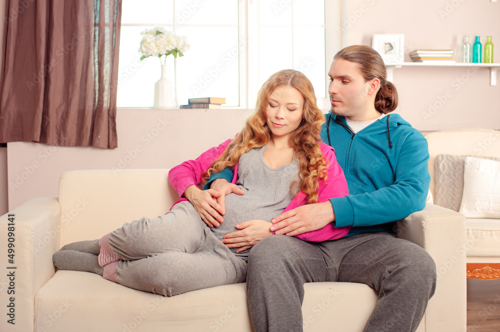 Young caucasian couple expecting a baby lying on the couch while enjoying the moment