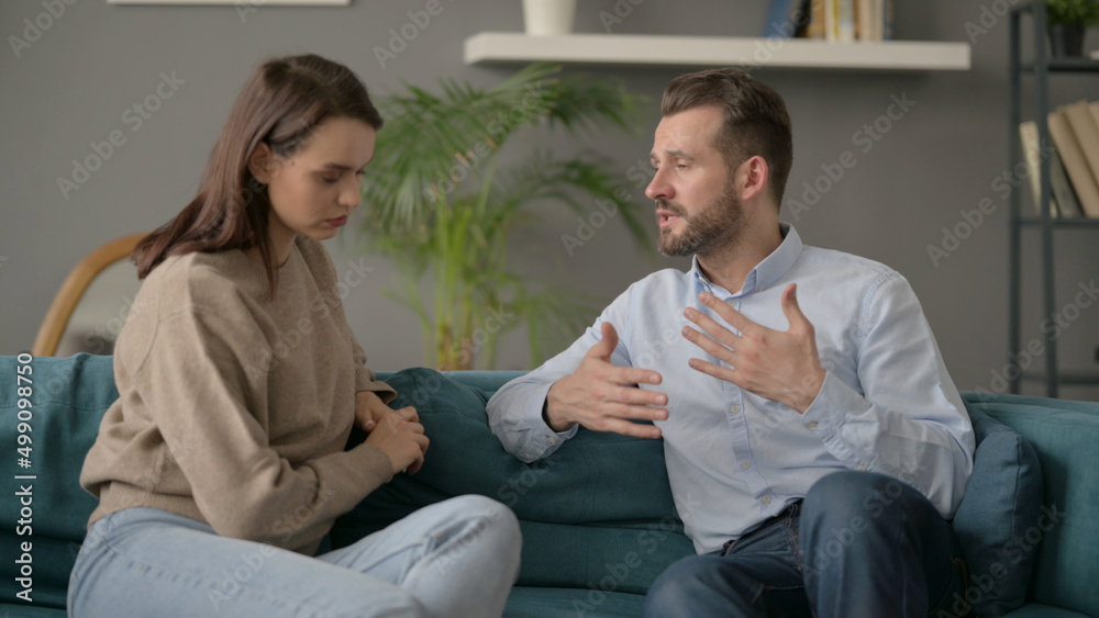 Fototapeta premium Serious Man Talking to Woman While Sitting on Sofa 