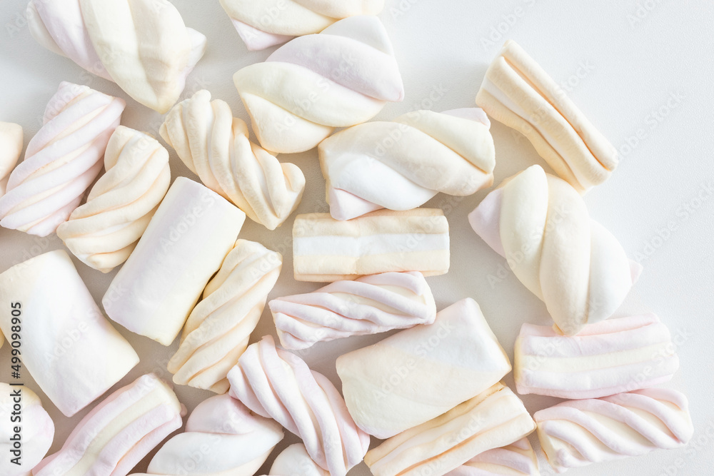 Obraz premium Colorful pastel marshmallow on white background. Ingredient for cooking dessert, snack for movie night and unhealthy sweets. Top view, copy space