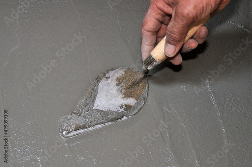 Worker's hand holding trowel, construction of building, building a wall