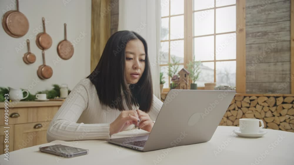 Young woman reading a positive message on her laptop in her apartment Young woman reading a positive message on her laptop in her apartment