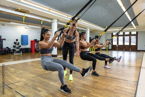 Sportswomen exercising with TRX ropes together