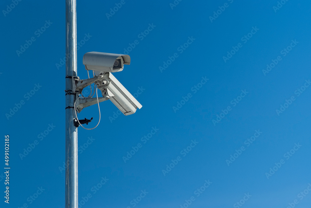 outdoor surveillance video camera, in the photo there are two video cameras against the blue sky outdoor surveillance video camera, in the photo there are two video cameras against the blue sky