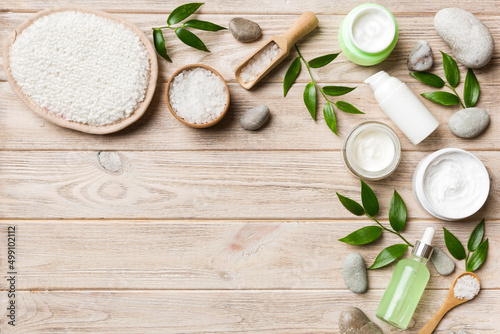 Coconut with jars of coconut oil and cosmetic cream on colored background. Top view. Free space for your text. Natural spa coconut cosmetics and organic treatment concept Coconut Spa composition