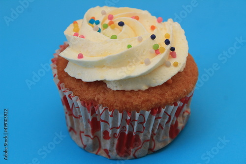 Sweet cake with tutti frutti sprinkles on top on the wooden table white background.