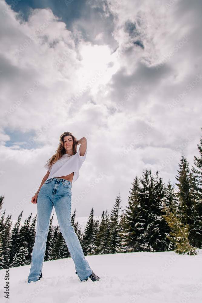 Beautiful Caucasian female in trendy fashion outfit posing against mountain forest Beautiful Caucasian female in trendy fashion outfit posing against mountain forest