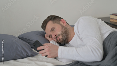 Man using Smartphone while Sleeping in Bed