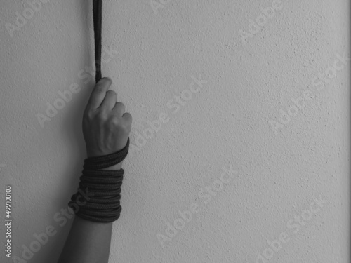 A woman's hand tied with a rope and suspended. Black and white photo. Selective focus