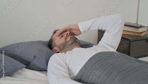 Man having Headache while Sleeping in Bed