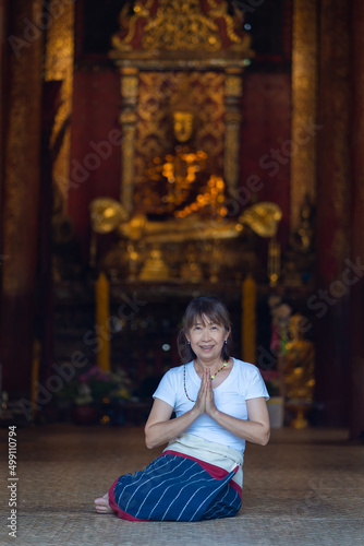 Asian Buddhist women pray, and make merit at Wat Ton Kain temple is the old wooden temple a famous place religious travel destination in Chiang Mai, Thailand.