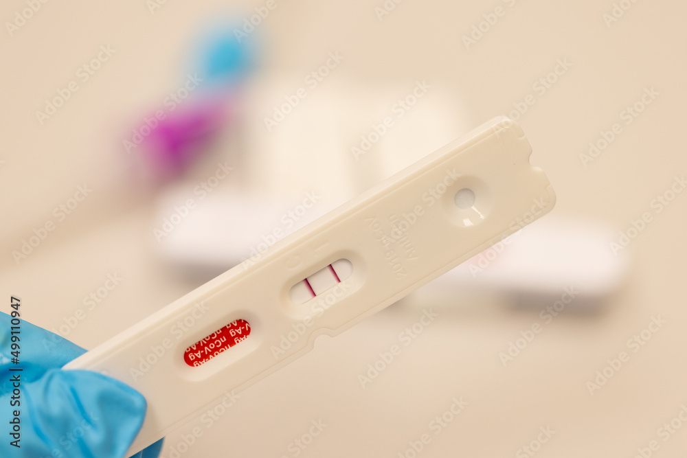 Doctor hand in glove hold Positive Result for coronavirus COVID-19 with test kit for viral disease. novel Lab card rapid omicron test. Selective focus Doctor hand in glove hold Positive Result for coronavirus COVID-19 with test kit for viral disease. novel Lab card rapid omicron test. Selective focus