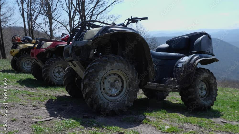 Dirty ATVs stand against the backdrop of mountain peaks. Smooth camera movement from right to left. Extreme type of outdoor activities. Touring rides on a quad bike Dirty ATVs stand against the backdrop of mountain peaks. Smooth camera movement from right to left. Extreme type of outdoor activities. Touring rides on a quad bike