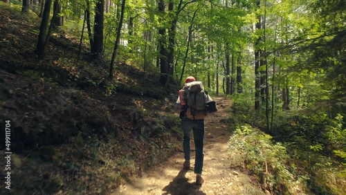 Following a hiker in a beautiful green forest with patches of sunshine on the path photo
