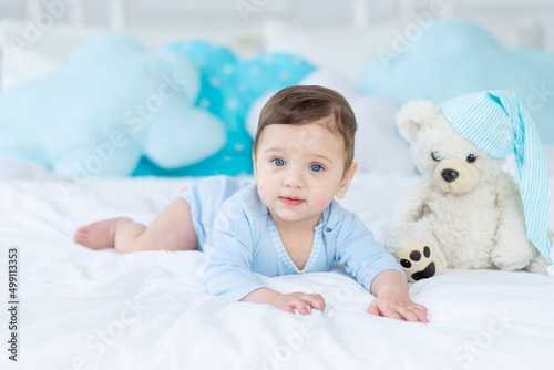 cute baby boy on the bed to sleep with teddy bear, baby room interior, healthy happy little baby