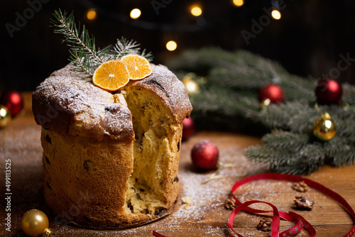 Rustic homemade Christmas traditional Italian holiday panettone cake with festive ribbon, decoration and lights